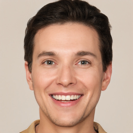 Joyful white young-adult male with short  brown hair and grey eyes