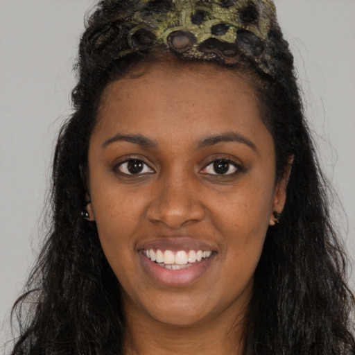 Joyful black young-adult female with long  brown hair and brown eyes