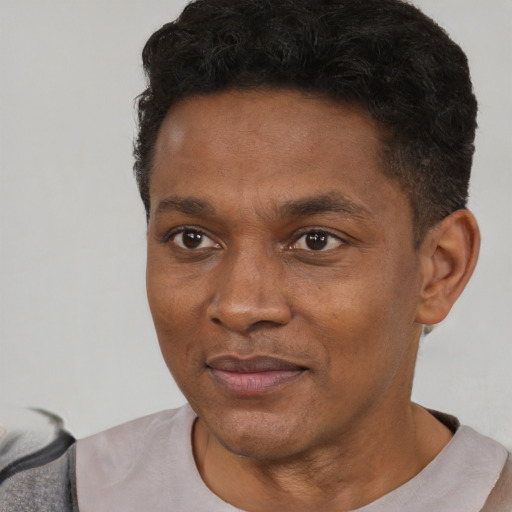Joyful black young-adult male with short  black hair and brown eyes