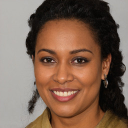 Joyful black young-adult female with long  brown hair and brown eyes