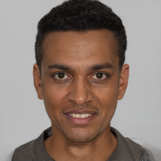 Joyful black young-adult male with short  black hair and brown eyes