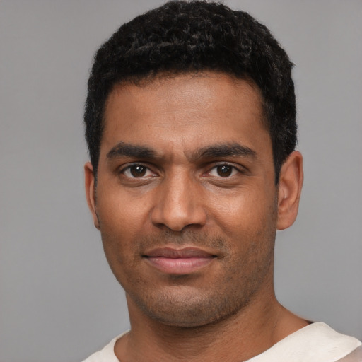 Joyful black young-adult male with short  black hair and brown eyes
