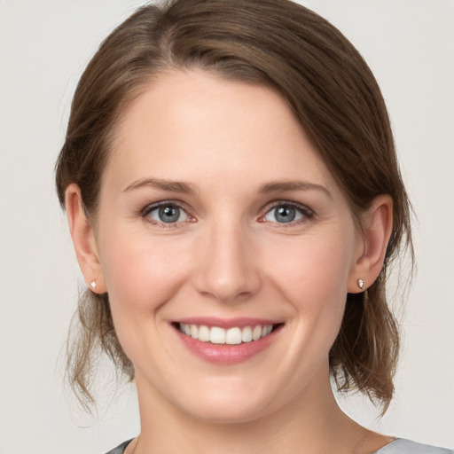 Joyful white young-adult female with medium  brown hair and grey eyes