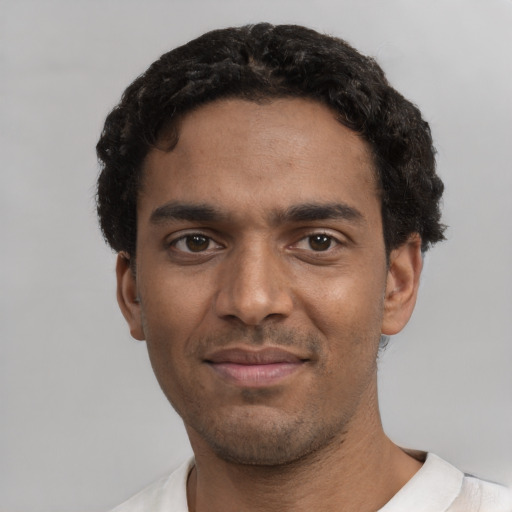 Joyful black young-adult male with short  black hair and brown eyes