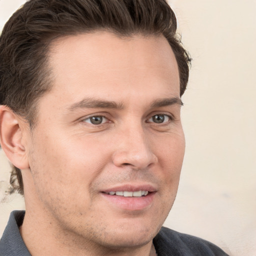 Joyful white young-adult male with short  brown hair and grey eyes