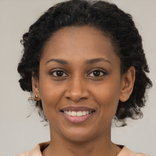 Joyful black young-adult female with short  black hair and brown eyes