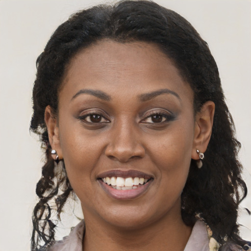 Joyful black young-adult female with long  brown hair and brown eyes