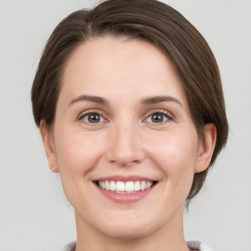 Joyful white young-adult female with medium  brown hair and green eyes