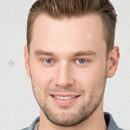 Joyful white young-adult male with short  brown hair and grey eyes