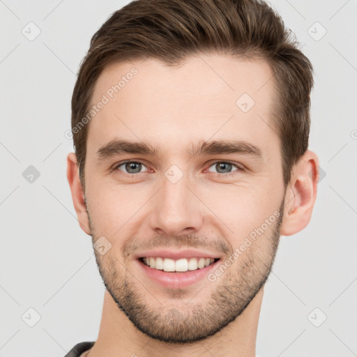 Joyful white young-adult male with short  brown hair and grey eyes