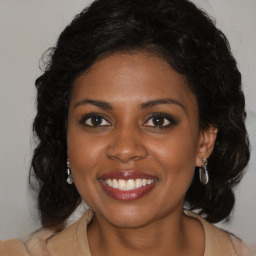 Joyful black young-adult female with long  brown hair and brown eyes