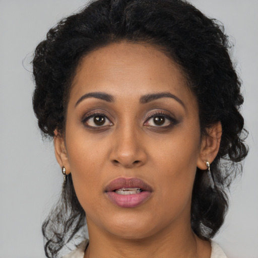 Joyful black young-adult female with long  brown hair and brown eyes
