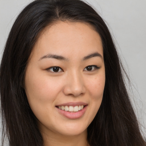 Joyful asian young-adult female with long  brown hair and brown eyes