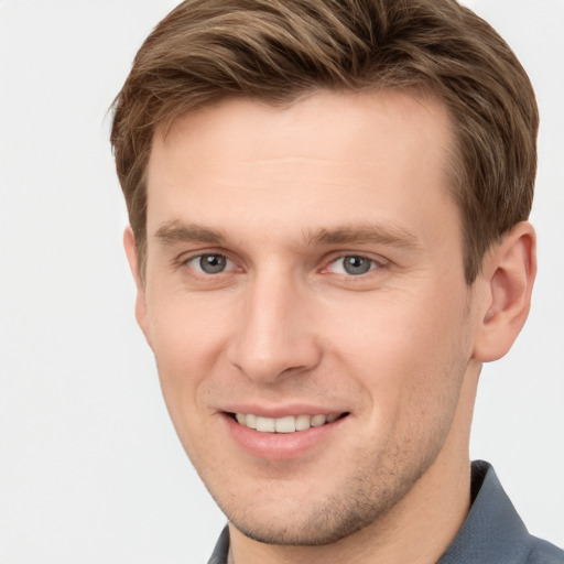 Joyful white young-adult male with short  brown hair and grey eyes