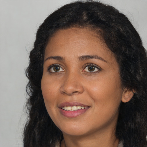 Joyful black young-adult female with long  brown hair and brown eyes
