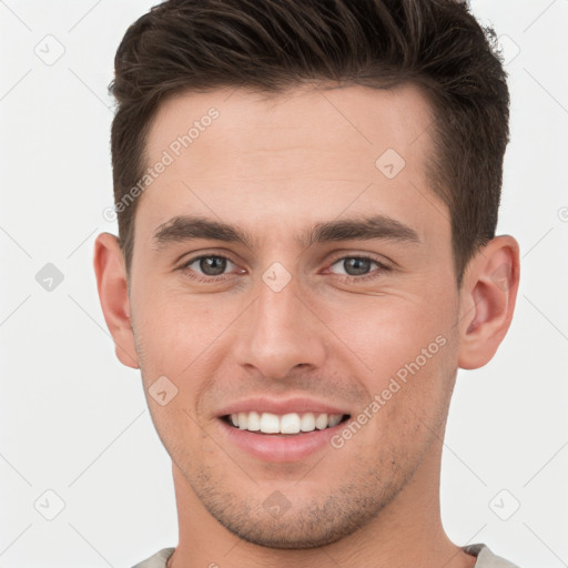 Joyful white young-adult male with short  brown hair and grey eyes