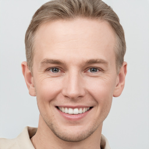 Joyful white young-adult male with short  brown hair and grey eyes