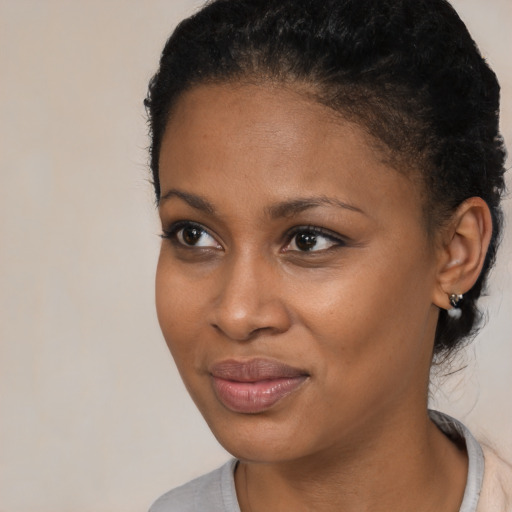 Joyful black young-adult female with short  black hair and brown eyes