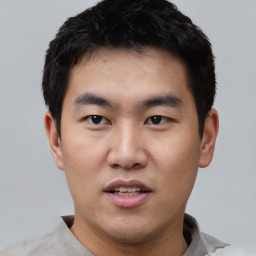 Joyful asian young-adult male with short  black hair and brown eyes