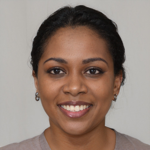 Joyful black young-adult female with short  black hair and brown eyes