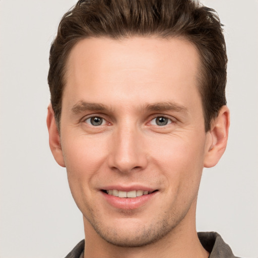 Joyful white young-adult male with short  brown hair and grey eyes