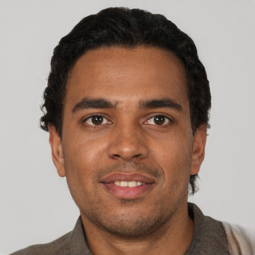 Joyful black young-adult male with short  black hair and brown eyes