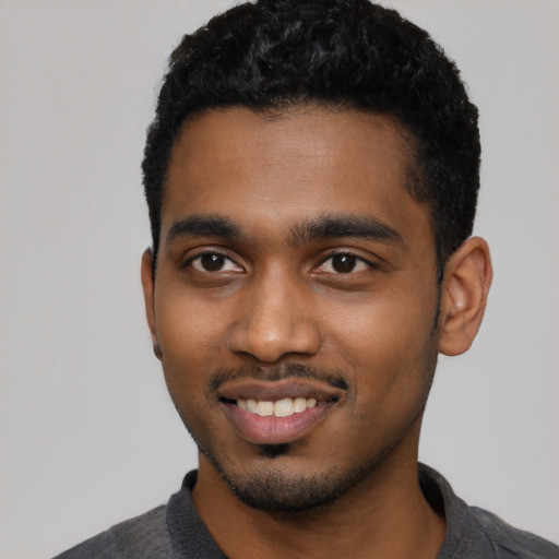 Joyful black young-adult male with short  black hair and brown eyes