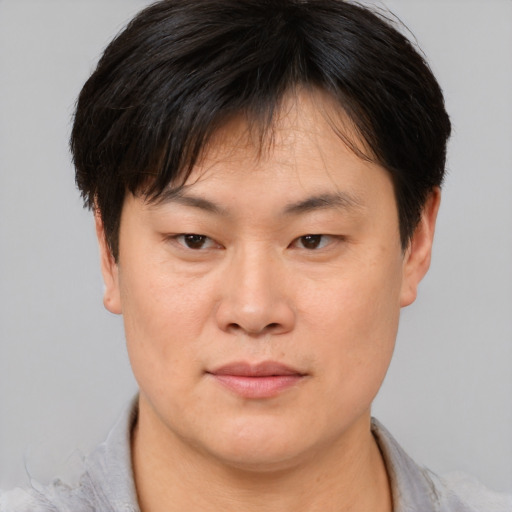 Joyful asian young-adult male with short  brown hair and brown eyes