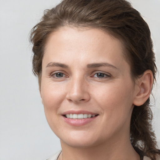 Joyful white young-adult female with medium  brown hair and grey eyes