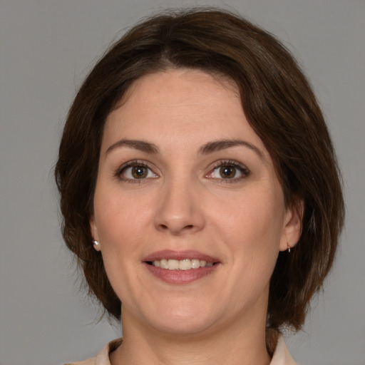 Joyful white adult female with medium  brown hair and green eyes