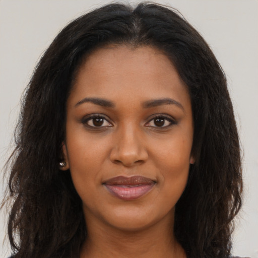 Joyful black young-adult female with long  brown hair and brown eyes