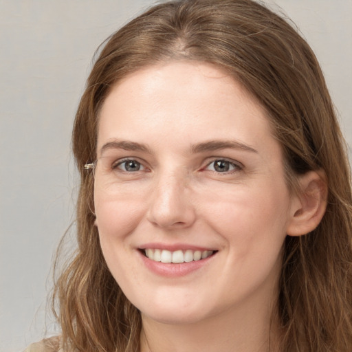 Joyful white young-adult female with long  brown hair and grey eyes