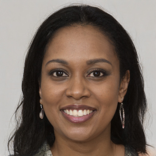 Joyful black young-adult female with long  brown hair and brown eyes