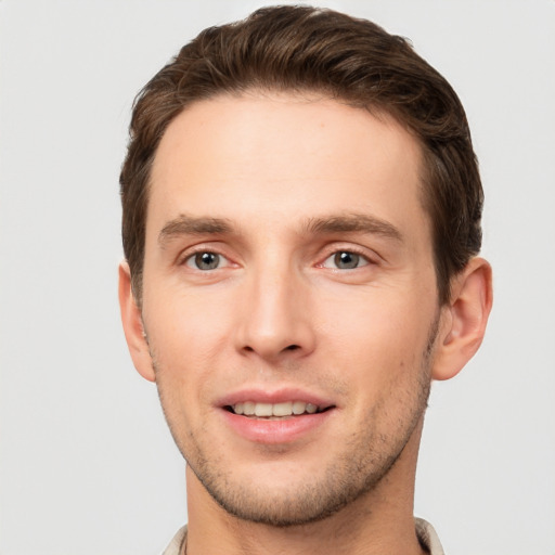 Joyful white young-adult male with short  brown hair and grey eyes