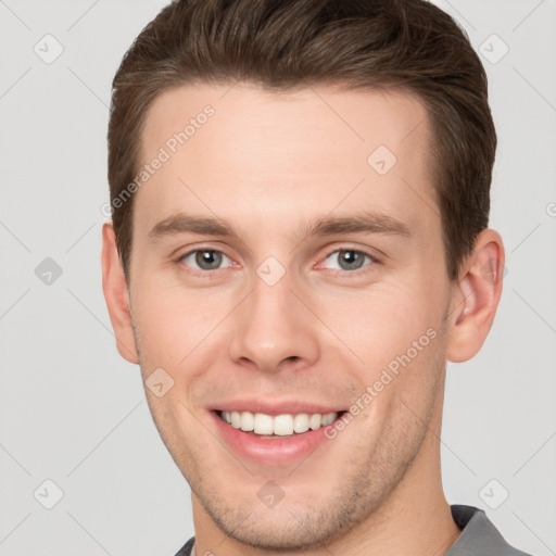 Joyful white young-adult male with short  brown hair and grey eyes