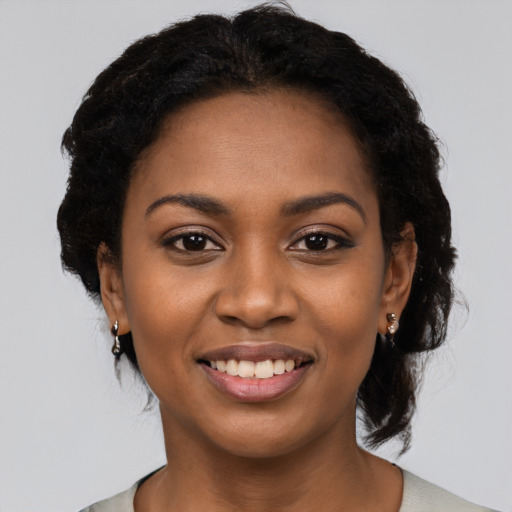 Joyful black young-adult female with long  black hair and brown eyes
