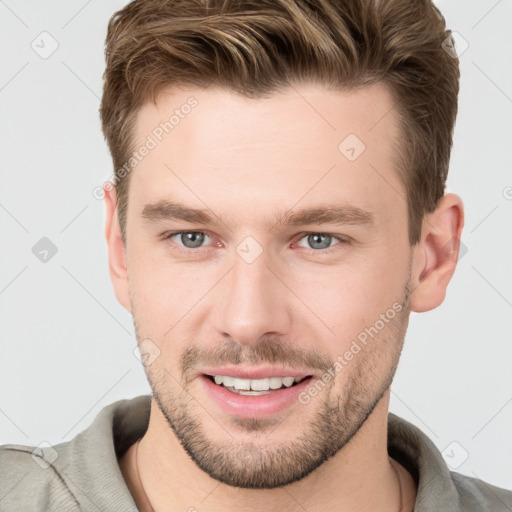 Joyful white young-adult male with short  brown hair and grey eyes