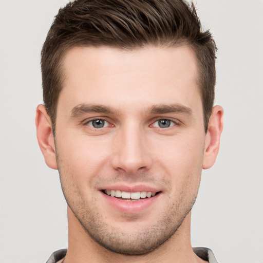 Joyful white young-adult male with short  brown hair and grey eyes