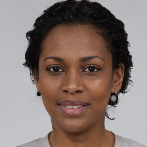 Joyful black young-adult female with short  black hair and brown eyes