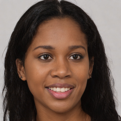 Joyful black young-adult female with long  brown hair and brown eyes