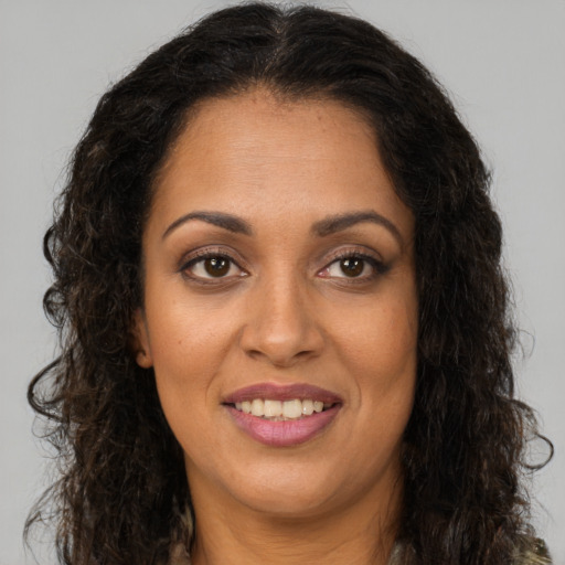 Joyful black young-adult female with long  brown hair and brown eyes