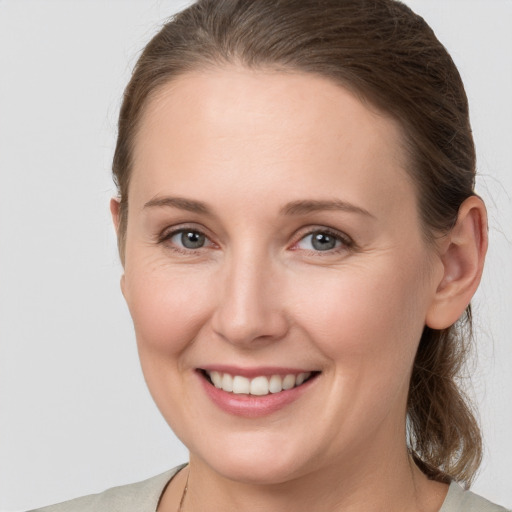 Joyful white young-adult female with medium  brown hair and grey eyes