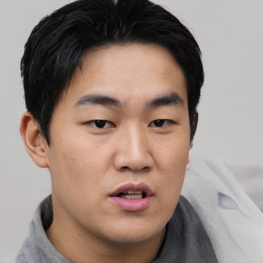 Joyful asian young-adult male with short  black hair and brown eyes
