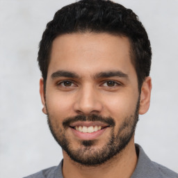 Joyful latino young-adult male with short  black hair and brown eyes