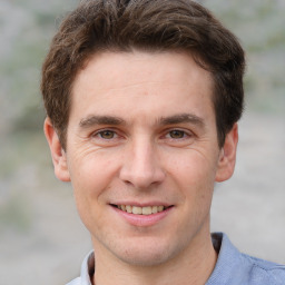 Joyful white young-adult male with short  brown hair and grey eyes