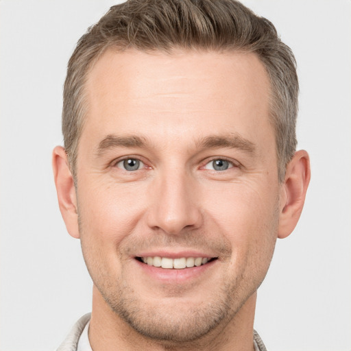 Joyful white young-adult male with short  brown hair and grey eyes