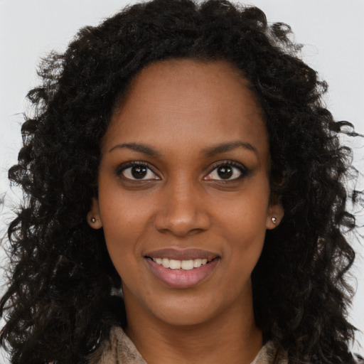 Joyful black young-adult female with long  brown hair and brown eyes