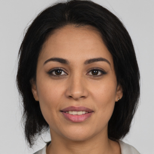 Joyful latino young-adult female with medium  brown hair and brown eyes