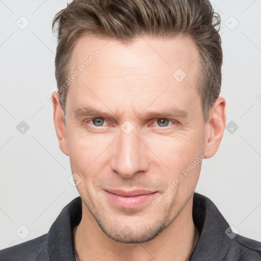 Joyful white adult male with short  brown hair and grey eyes