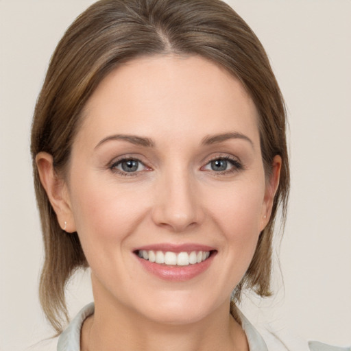 Joyful white young-adult female with medium  brown hair and grey eyes